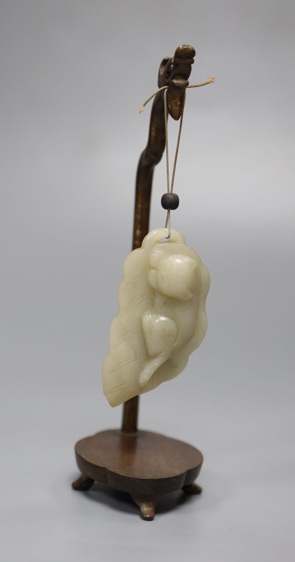 A 19th century Chinese celadon jade figure of a cat on a leaf, wood stand, height 17cm